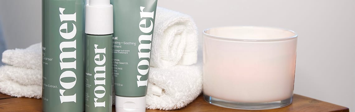 Romer Skincare products next to a towel and a candle